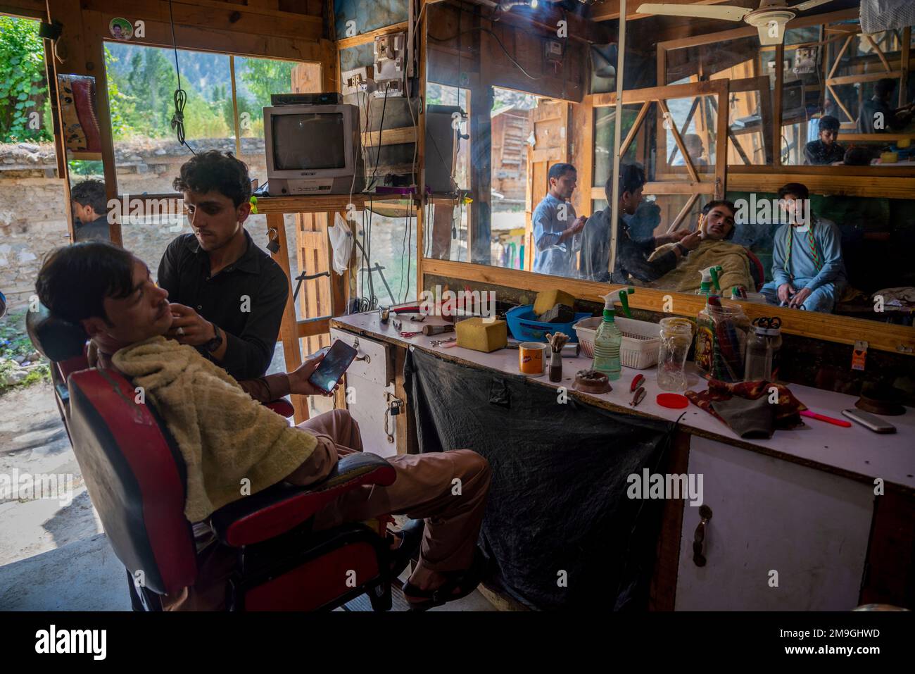 Clienti serviti in un barbiere nella zona di Kalash, Bumburet Valley, Pakistan Foto Stock