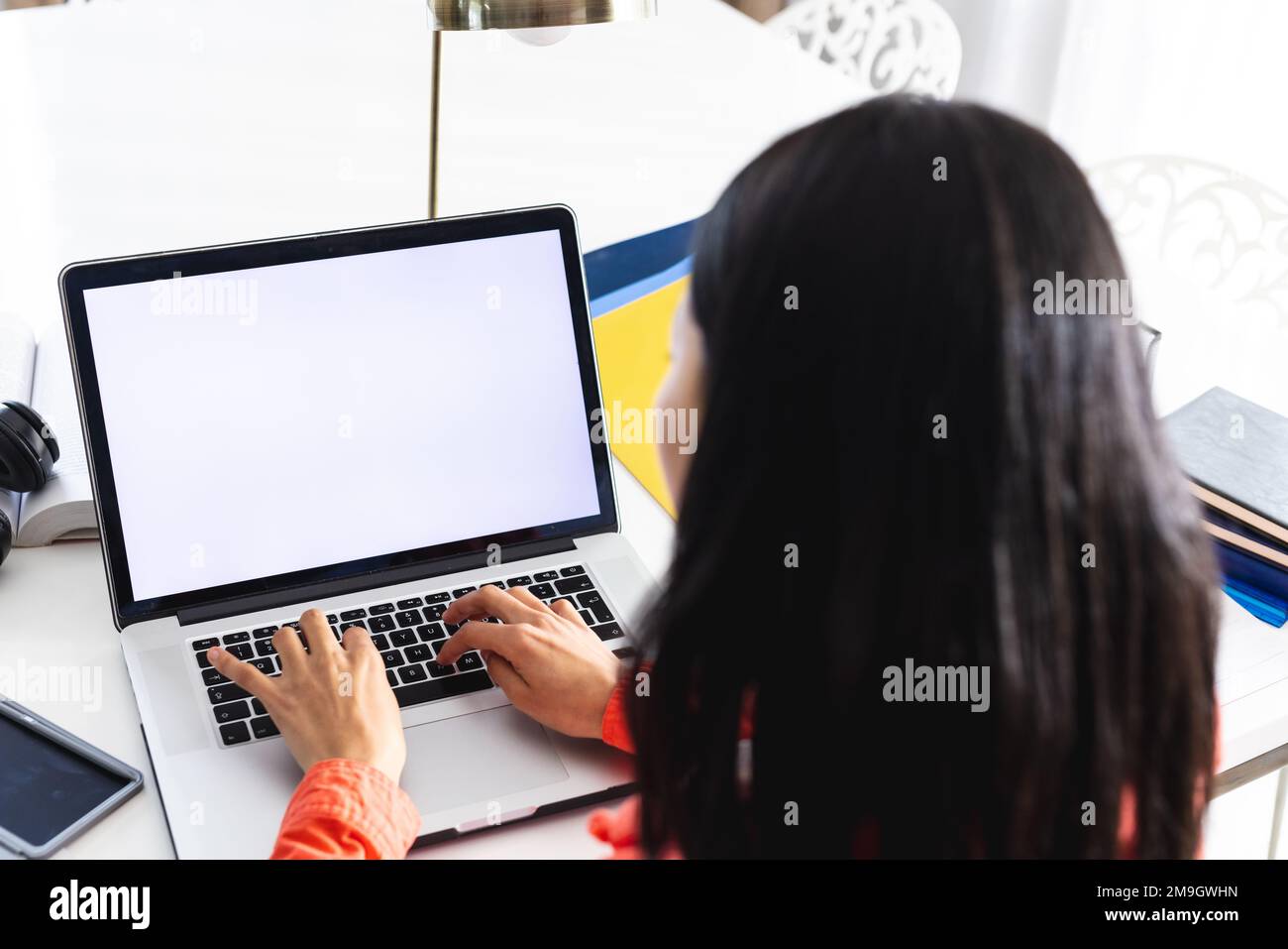 Immagine di una donna biraciale che utilizza un computer portatile con spazio copia sullo schermo seduto alla scrivania Foto Stock