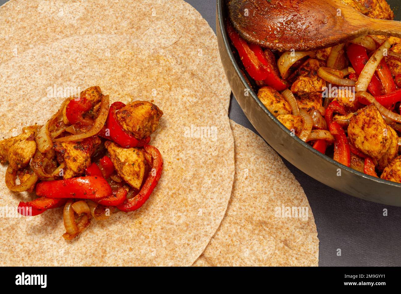 Fajitas di pollo, pepe rosso e cipolla con cucchiaio di legno Foto Stock