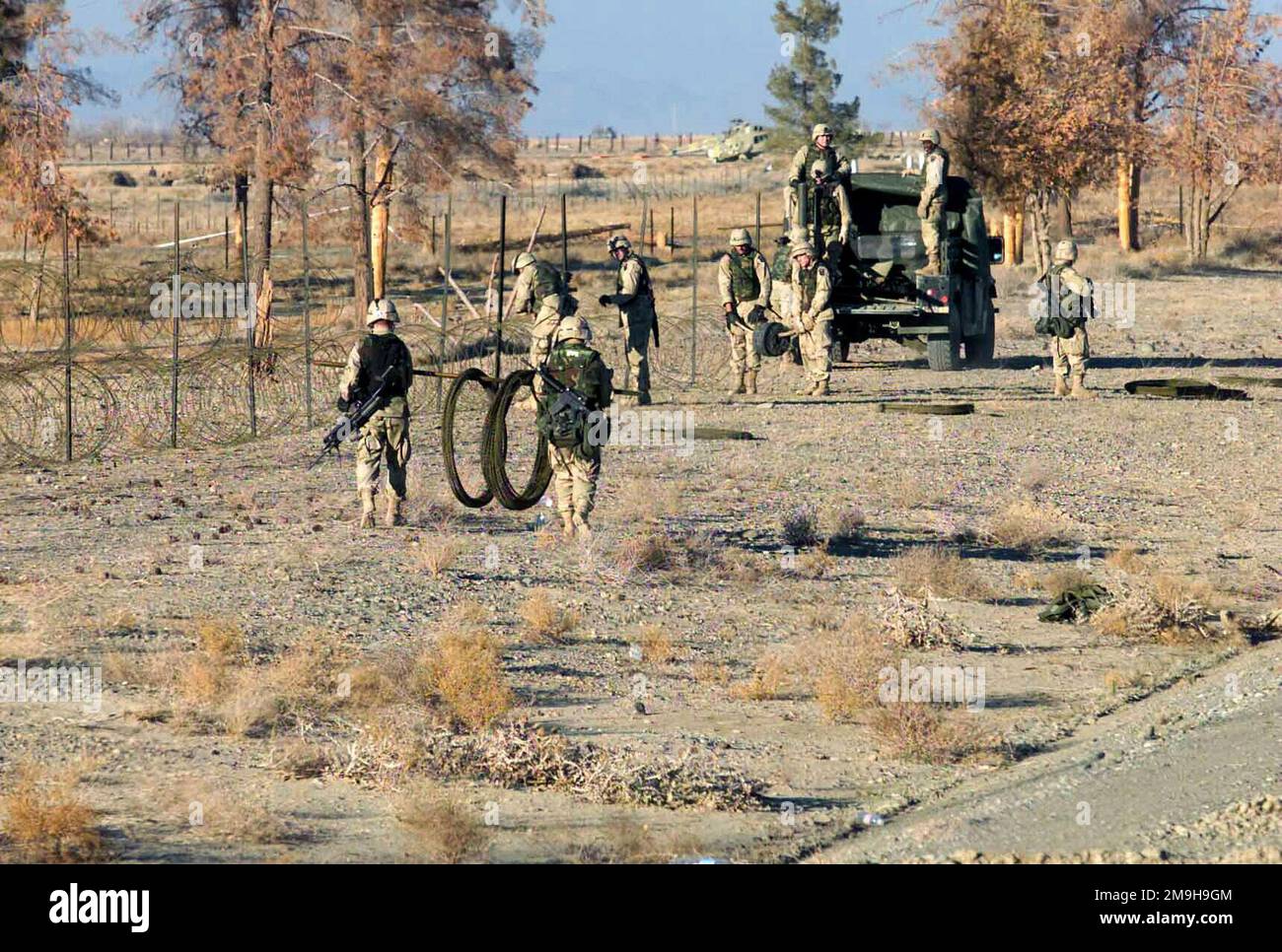 I soldati dell'esercito rafforzano le misure di protezione della forza, ponendo più file di filo di concertina intorno all'aeroporto internazionale di Kandahar, Kandahar, Afghanistan, durante L'OPERAZIONE CHE PERSEGUE LA LIBERTÀ. Tutti i personaggi dell'esercito trasportano M16s e uno ha una SEGA M-240B (arma automatica della squadra), mentre scaricano il veicolo a ruote multiuso ad alta mobilità M1097 (HMMWV). Soggetto operativo/Serie: ENDURING FREEDOM base: Aeroporto Internazionale di Kandahar Paese: Afghanistan (AFG) Foto Stock