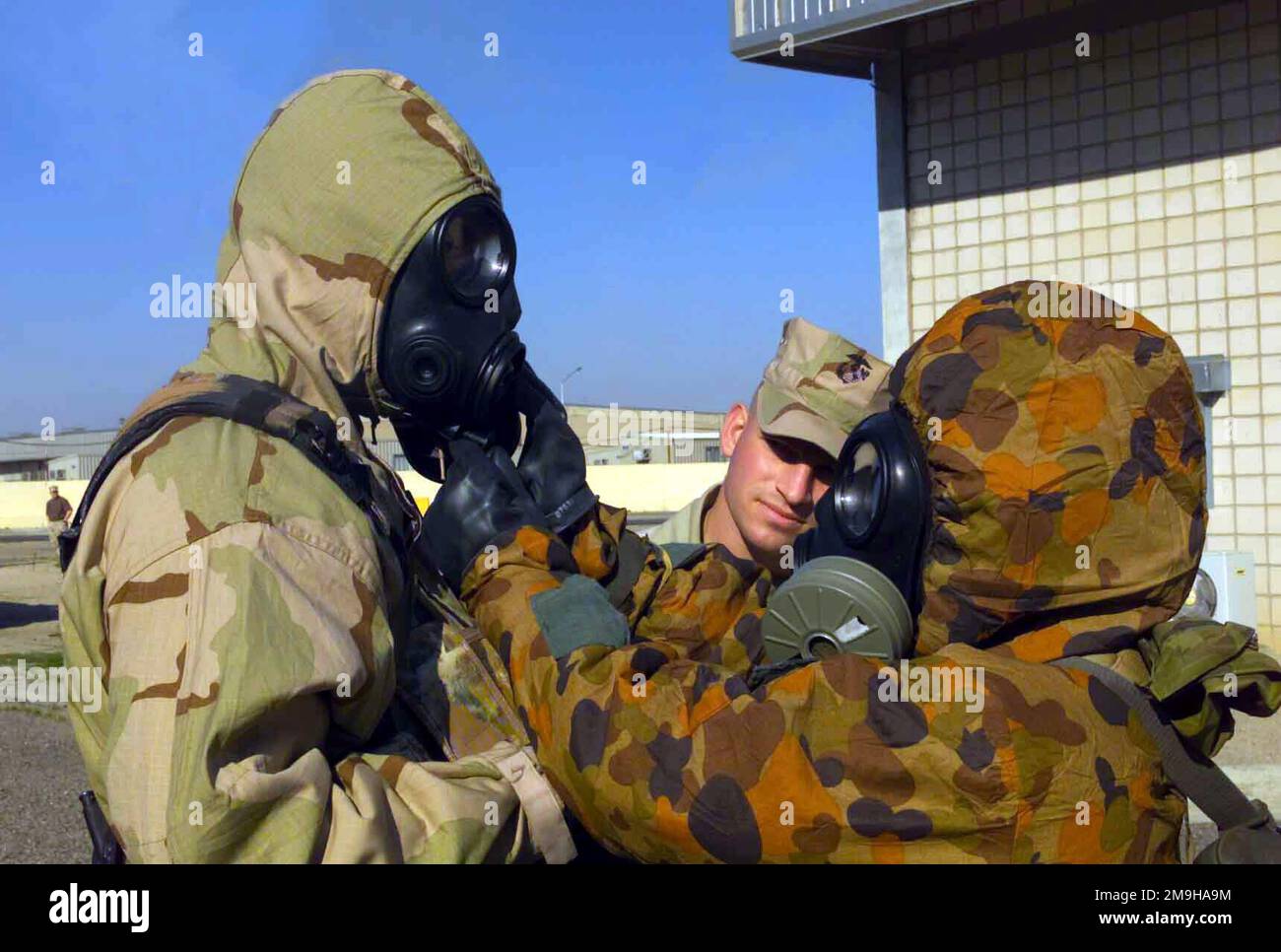 Il sergente Robert T. Mawson osserva come Marine con la Combined Joint Task Force (CJTF), nel suo Joint Service Lightweight Integrated Suit Technology (JSLIST), indossando una maschera da campo chimico-biologico M40 con un filtro C2A1, ottiene assistenza mettendo via il suo tubo da bere da un membro di servizio australiano. L'australiano indossa la tuta MKIV No1 NBC (Nuclear Biological Chemical) con la maschera Avon FM12. Entrambi si stanno allenando a Camp Doha, in Kuwait, durante LE OPERAZIONI CHE DURANO LA LIBERTÀ. Subject Operation/Series: ENDURING FREEDOM base: Camp Doha Paese: Kuwait (KWT) Scene Major Command mostrato: CJTF Foto Stock