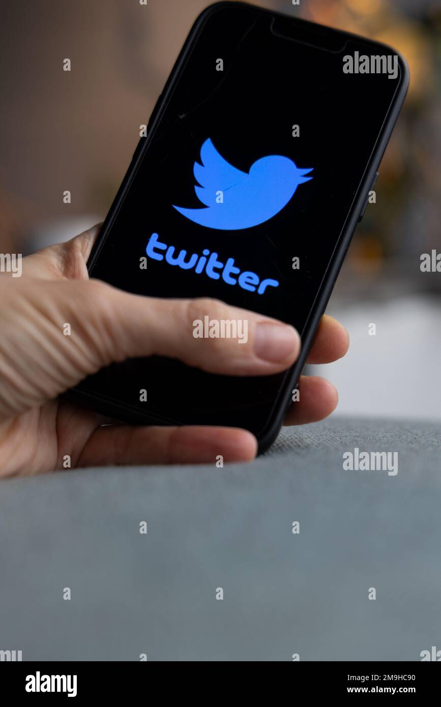 Tenere in mano uno smartphone con l'icona Twitter sullo schermo. Uccello blu e parola Twitter su schermo nero. IPhone con il logo di un'app per social media. Amsterdam, Net Foto Stock