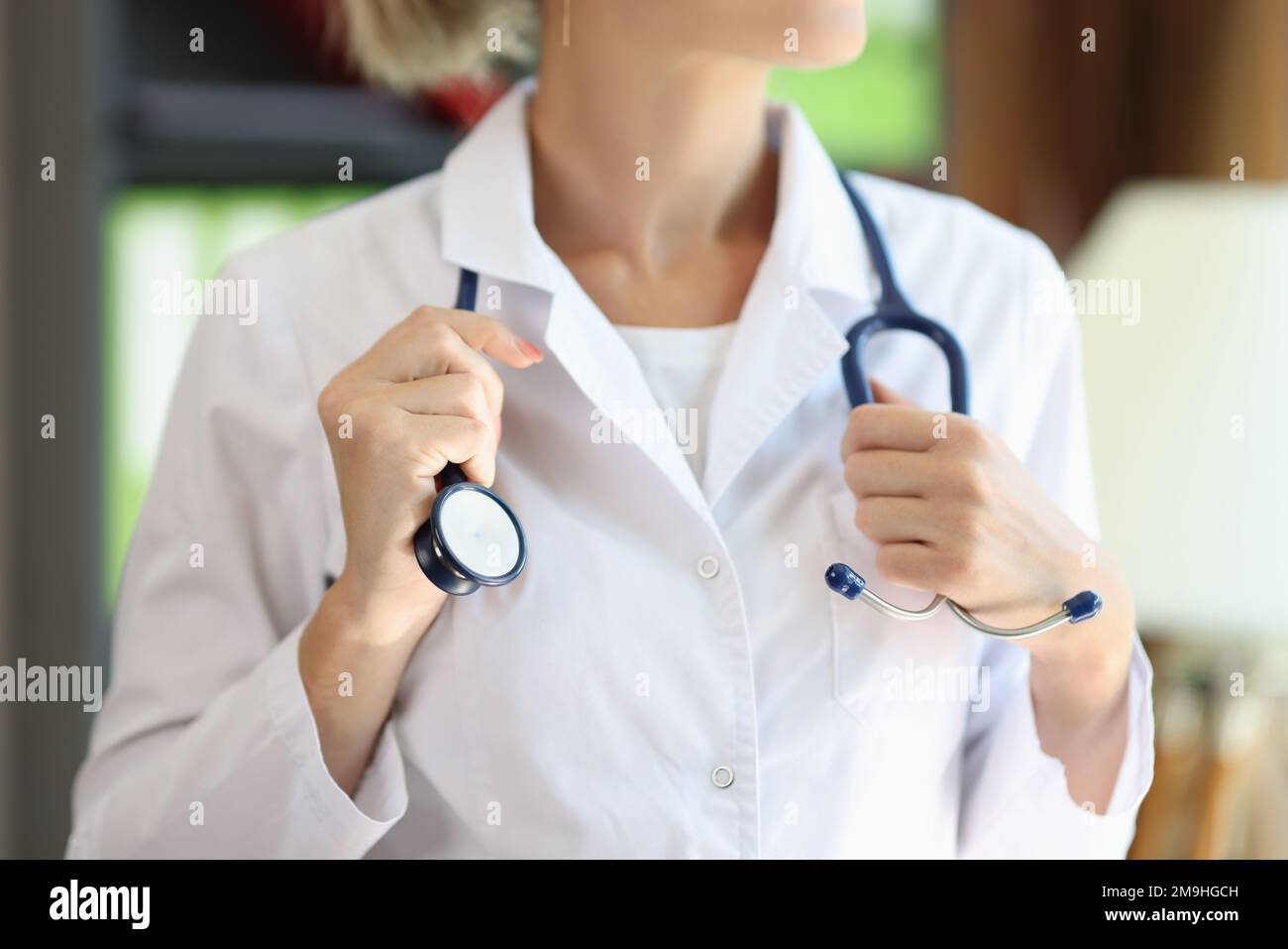 Primo piano della cardiologa femminile che tiene il suo stetoscopio in ospedale. Foto Stock