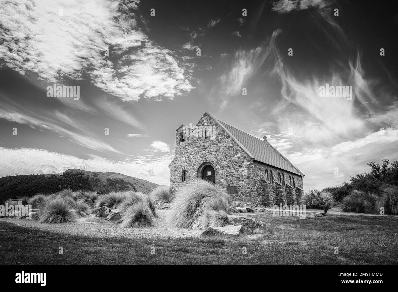 Immagine in bianco e nero di nuvole e cielo blu dietro la Chiesa del buon Pastore sulle rive del lago Tekapo in Nuova Zelanda Foto Stock