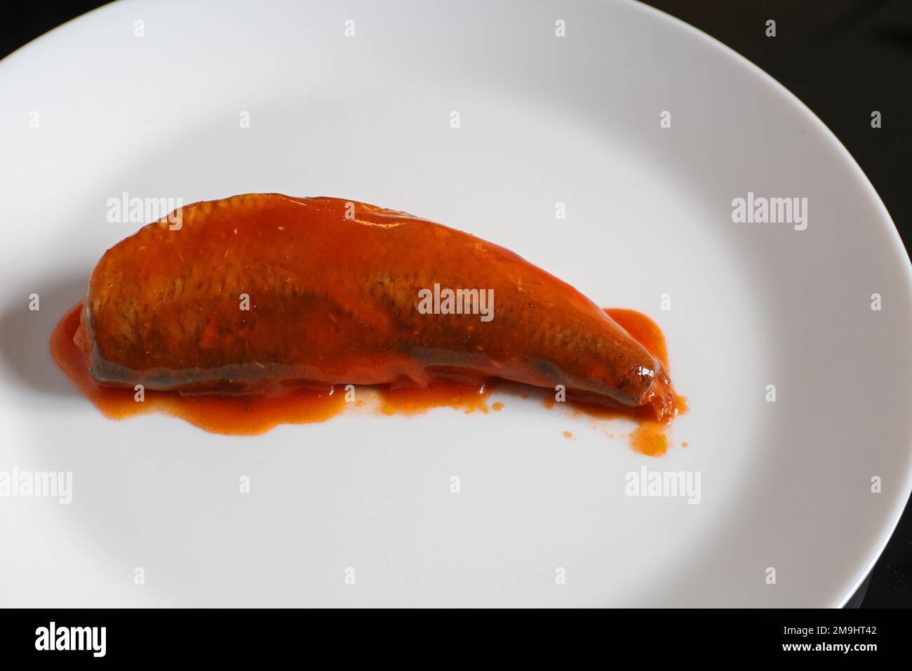 Sardine in salsa di pomodoro su un piatto bianco. Sardine in scatola. Foto Stock