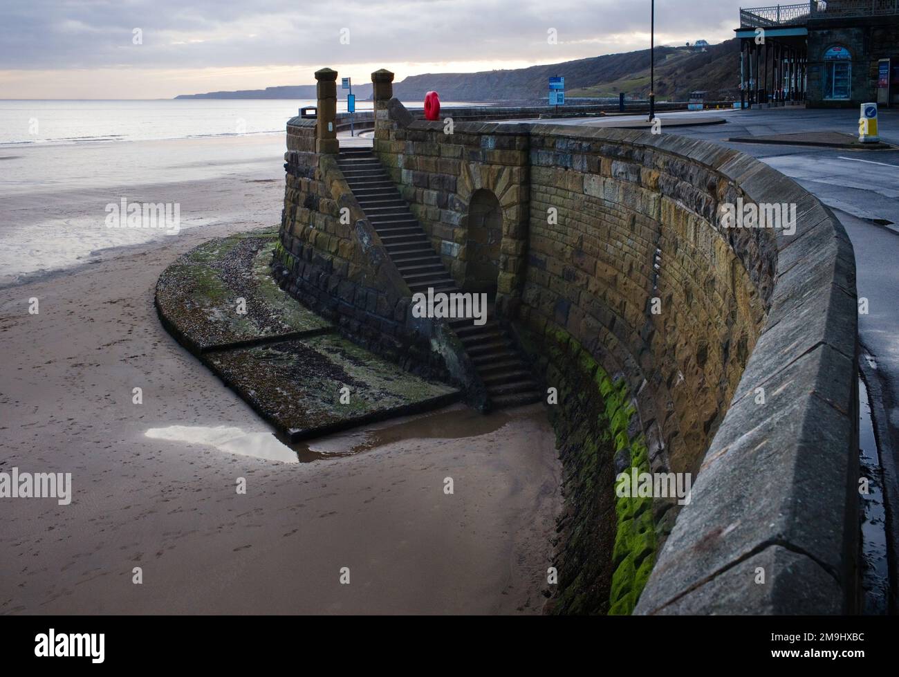 Muro di mare con scalini che portano al rubinetto o al getto d'acqua libero originale presso la Scarborough Spa Foto Stock