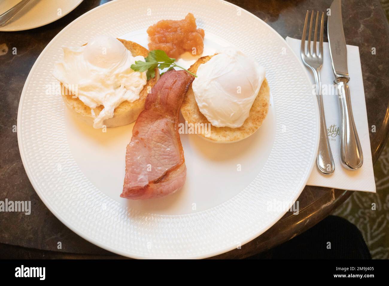Spuntino mattutino in una caffetteria muffin per la colazione con uova in camicia e chutney di mele Foto Stock