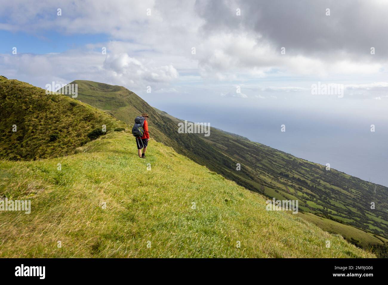 Persona escursionismo lungo un vecchio bordo del cratere vulcanico sull'isola di São Jorge nelle Azzorre Foto Stock