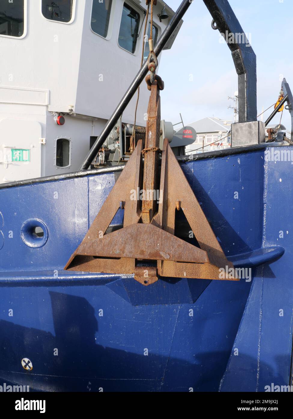 Grande ancora arrugginita angolare su uno scafo blu di una gru nel porto di Burg auf Fehmarn Germania Foto Stock