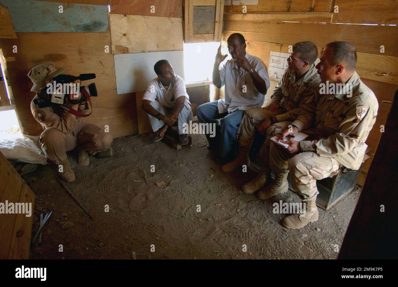 030205-F-7203T-010. [Completa] Scene Caption: US Air Force (USAF) STAFF Sergeant (SSGT) Dawn Anderson (a sinistra), video di combattimento, 1st Combat Camera Squadron (CCS), Charleston Air Force base (AFB), South Carolina (SC), documenti US Army (USA) Sergeant First Class (SFC) Steven Ruscitto (a destra) e USA Sergeant (SGT, Joseph Civil Brigade), 354th) US Army Reserve, Riverdale, Maryland (MD), all'interno della casa di Omar Farah Dabar, CAPO del villaggio Sud Homboli, Gibuti. IL CAPO Dabar ha recentemente costruito l'aggiunta di 10 piedi alla sua casa utilizzando legno donato dai membri militari statunitensi per la prima volta Foto Stock