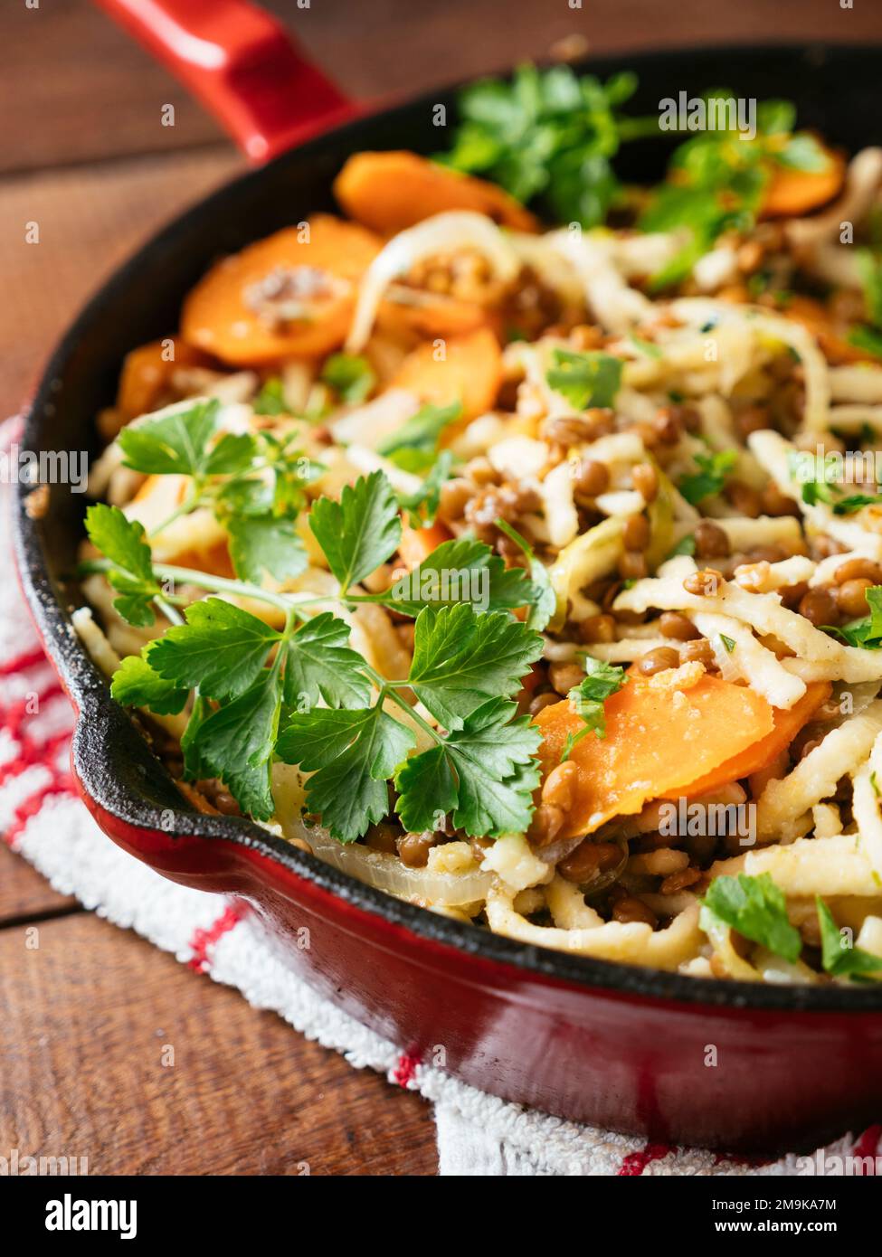 Carote e lenticchie con pasta tedesca (Spaetzle) in una padella di ghisa. Foto Stock