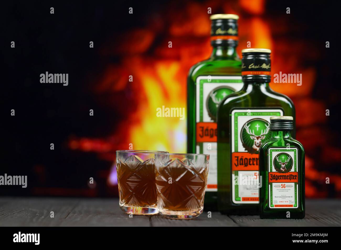 KIEV, UCRAINA - 4 MAGGIO 2022 Jagermeister bottiglia di alcol originale su tavolo di legno con camino rosso sullo sfondo. Produzione di alcool Elite Foto Stock