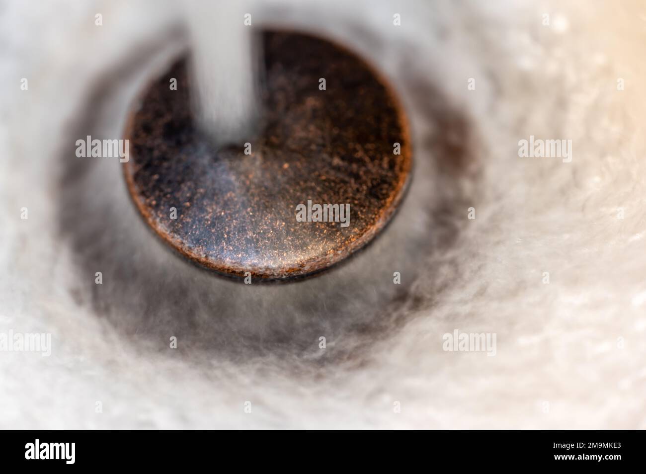 Caduta di acqua su uno scarico del lavandino aperto. Foto Stock