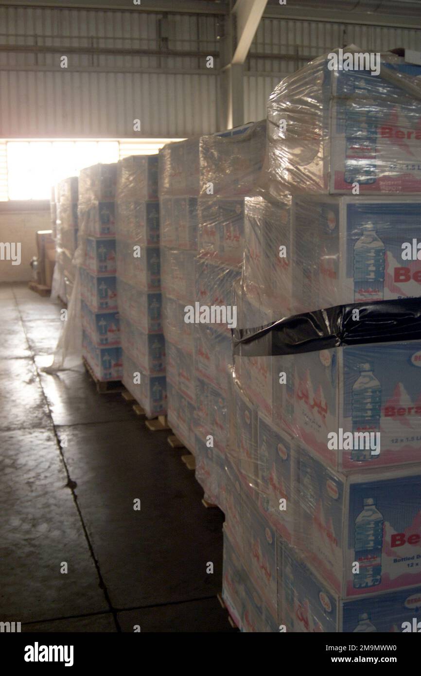 Pallet di acqua in bottiglia e assistenza umanitaria, in attesa di essere consegnati ai cittadini iracheni, sono immagazzinati in un magazzino nella città di Umm Qasr, Iraq, durante l'operazione IRACHENA LIBERTÀ. Soggetto operativo/Serie: BASE PER LA LIBERTÀ IRACHENA: Umm Qasr Paese: Iraq (IRQ) Foto Stock