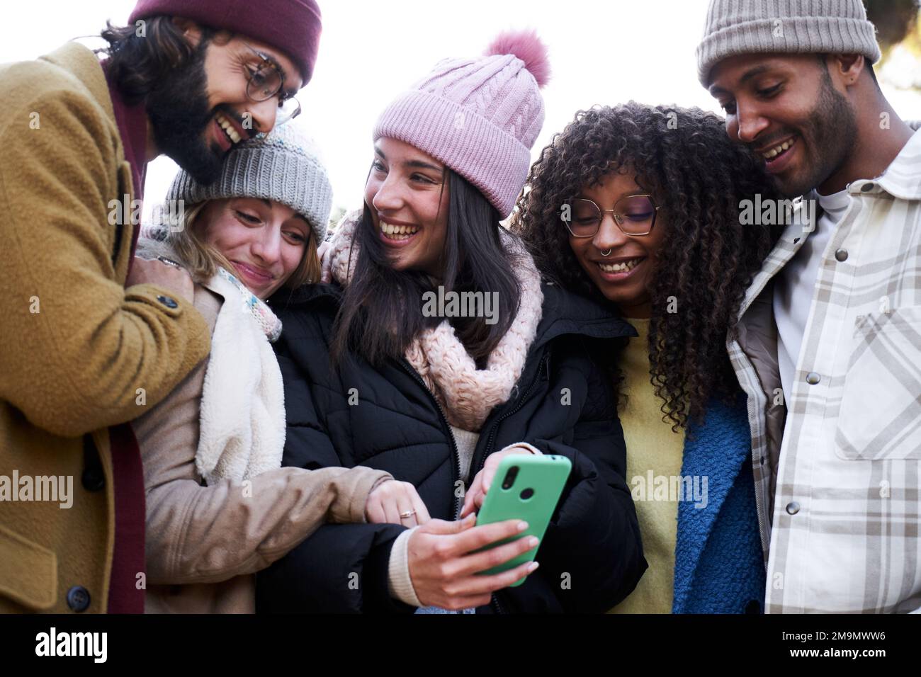 Gruppo di amici multietnici che guardano il telefono cellulare, ridono e condividono. Foto Stock