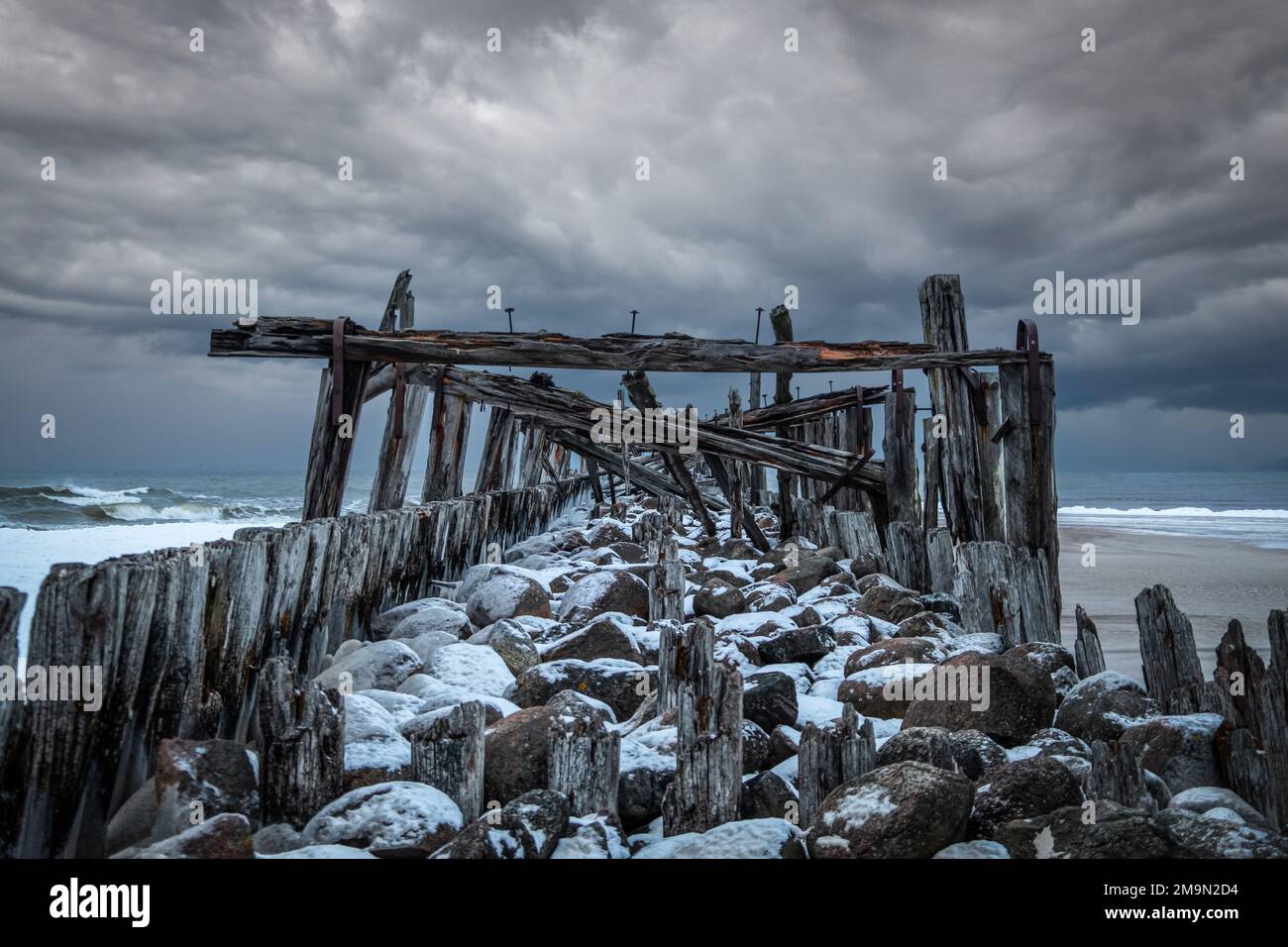 Nuvole d'inverno tempestose e un antico ponte sul Mar Baltico a Šventoji, Lituania Foto Stock