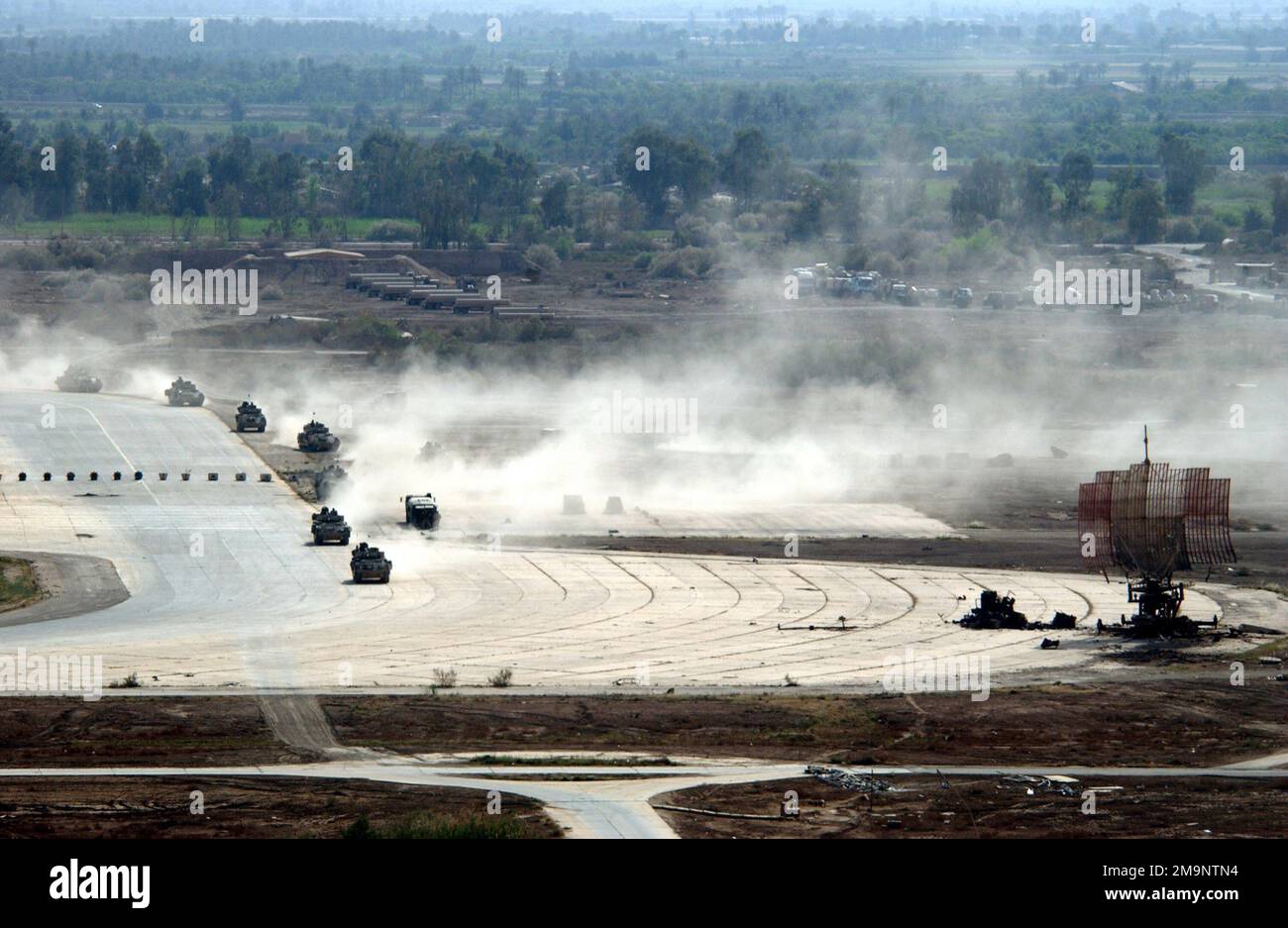 La polvere sale nell'aria mentre un convoglio di veicoli blindati dell'esercito degli Stati Uniti (USA) si sposta attraverso la linea di volo all'aeroporto internazionale di Baghdad (IAP), in Iraq, durante l'operazione LA LIBERTÀ IRACHENA. L'IAP di Baghdad è la base principale delle operazioni per le truppe militari statunitensi, le merci e gli aiuti umanitari che vengono trasportate in Iraq centrale. Soggetto operativo/Serie: BASE PER LA LIBERTÀ IRACHENA: Aeroporto internazionale di Baghdad Paese: Iraq (IRQ) Foto Stock