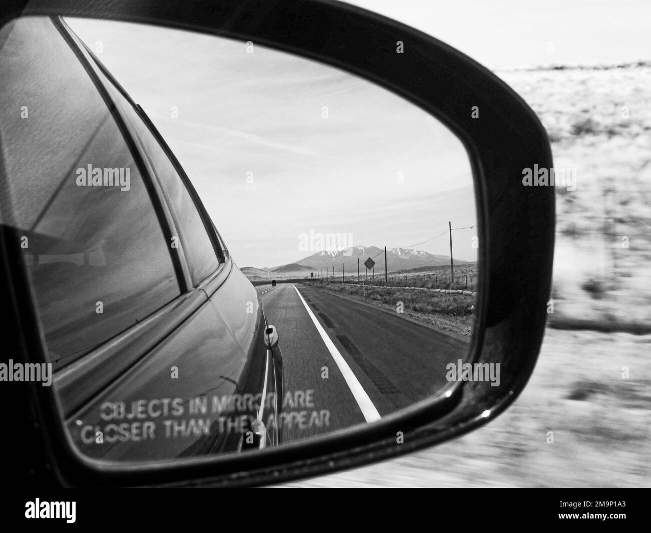 Un'immagine in scala di grigi dello specchio dell'ala dell'automobile durante un viaggio in Arizona, Stati Uniti Foto Stock