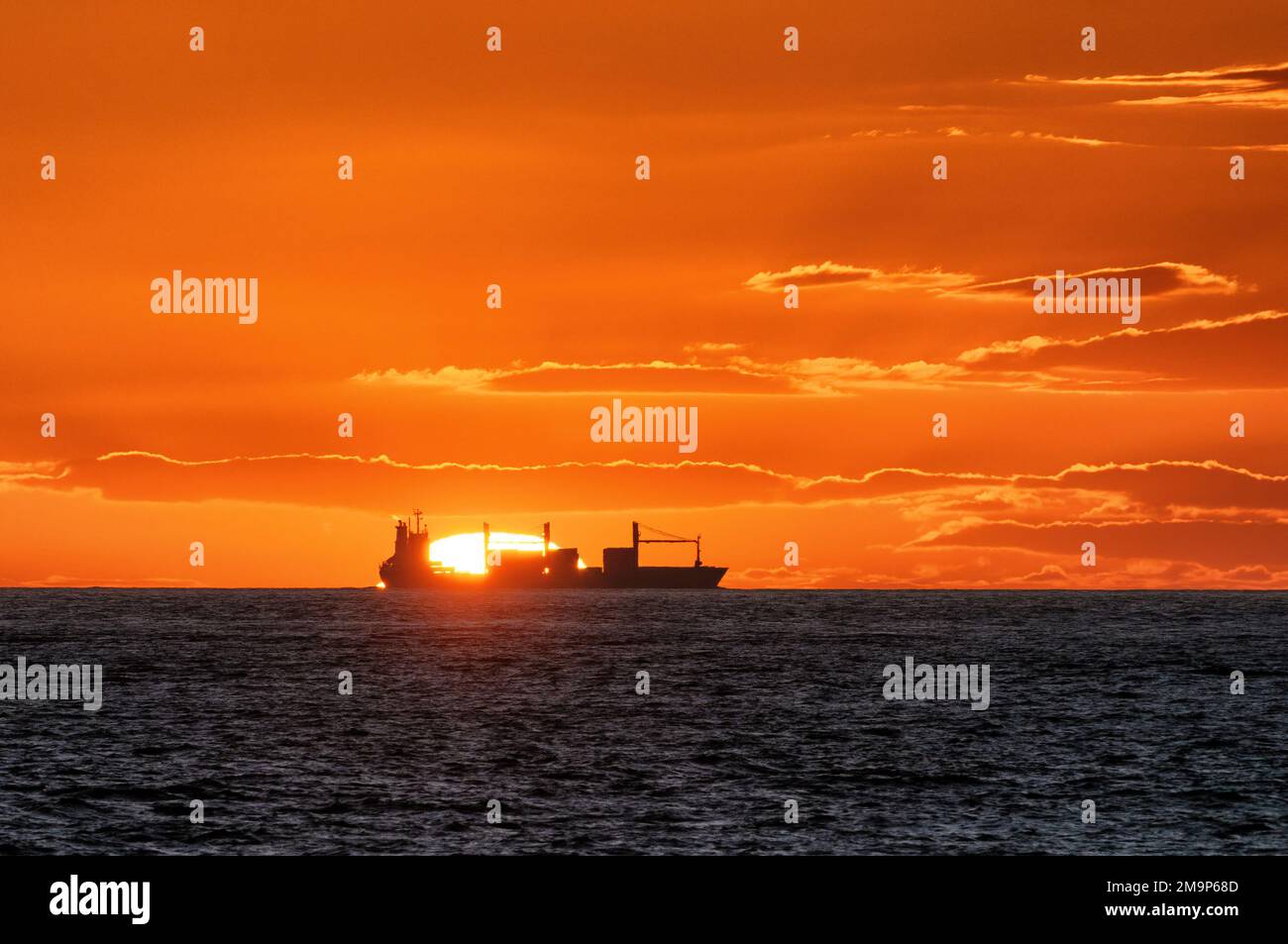 Una nave da carico generale in mare, con un tramonto mozzafiato. Foto Stock