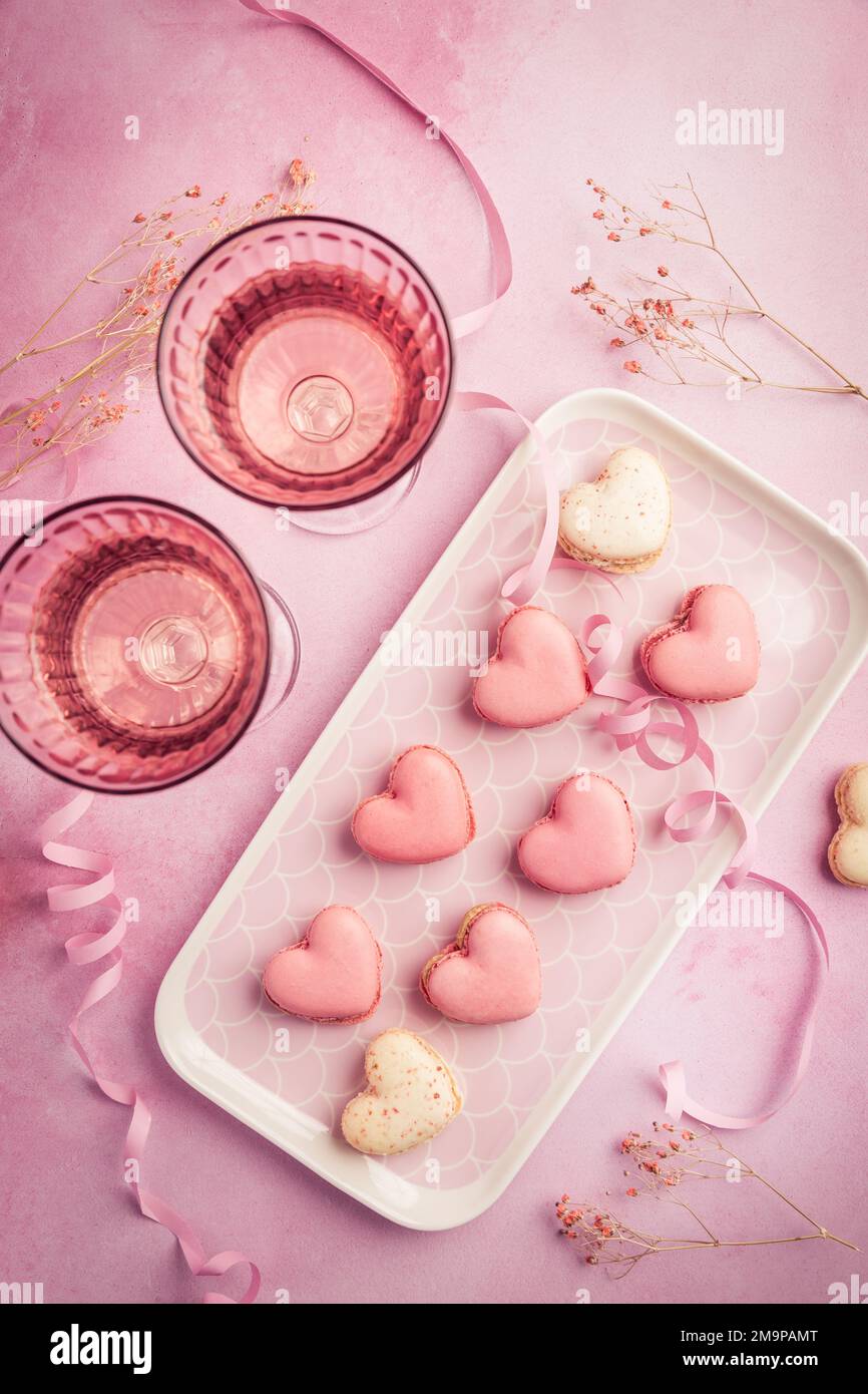 Buon giorno della mamma, buon San Valentino - amaretti dolci a forma di cuore e bicchieri di spumante rosa in tonalità rosa Foto Stock