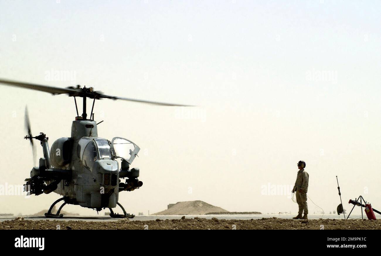 US Marine Corps (USMC) Lance Corporal (LCPL) John Ideus, Marine Wing Support Squadron Three Seven One (MWSS-371) aspetta di alimentare l'elicottero Aah-1W Super Cobra ad un punto di rifornimento di zona di andata (FARP), alla base aerea di tallil, Iraq durante l'operazione LA LIBERTÀ IRACHENA. Soggetto operativo/Serie: BASE PER LA LIBERTÀ IRACHENA: Base aerea di tallil Stato: Dhi Qar Paese: Iraq (IRQ) Foto Stock