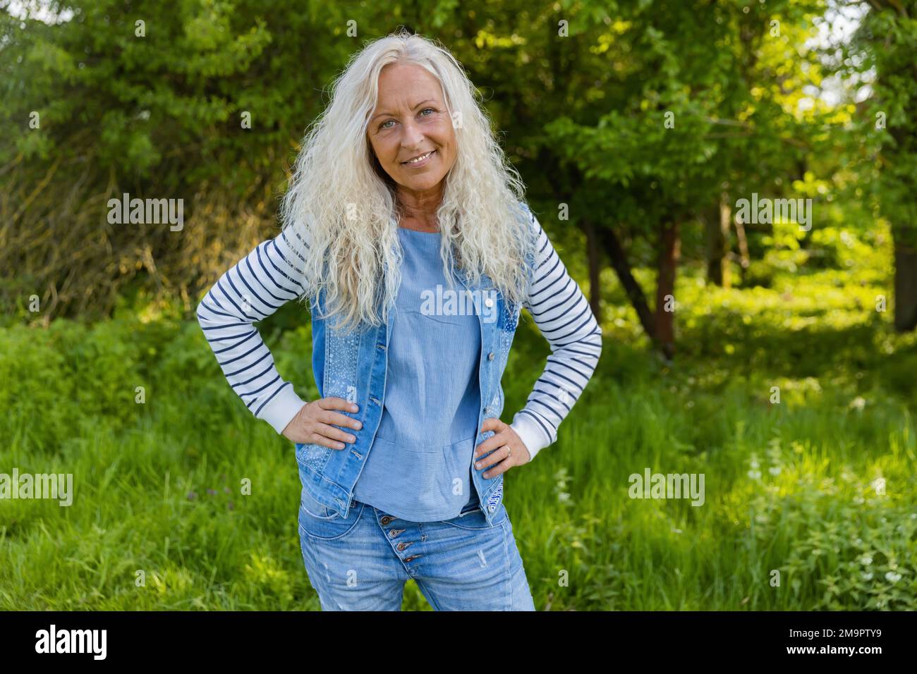 Bella donna con piercing tenere le braccia ai fianchi. Foto Stock