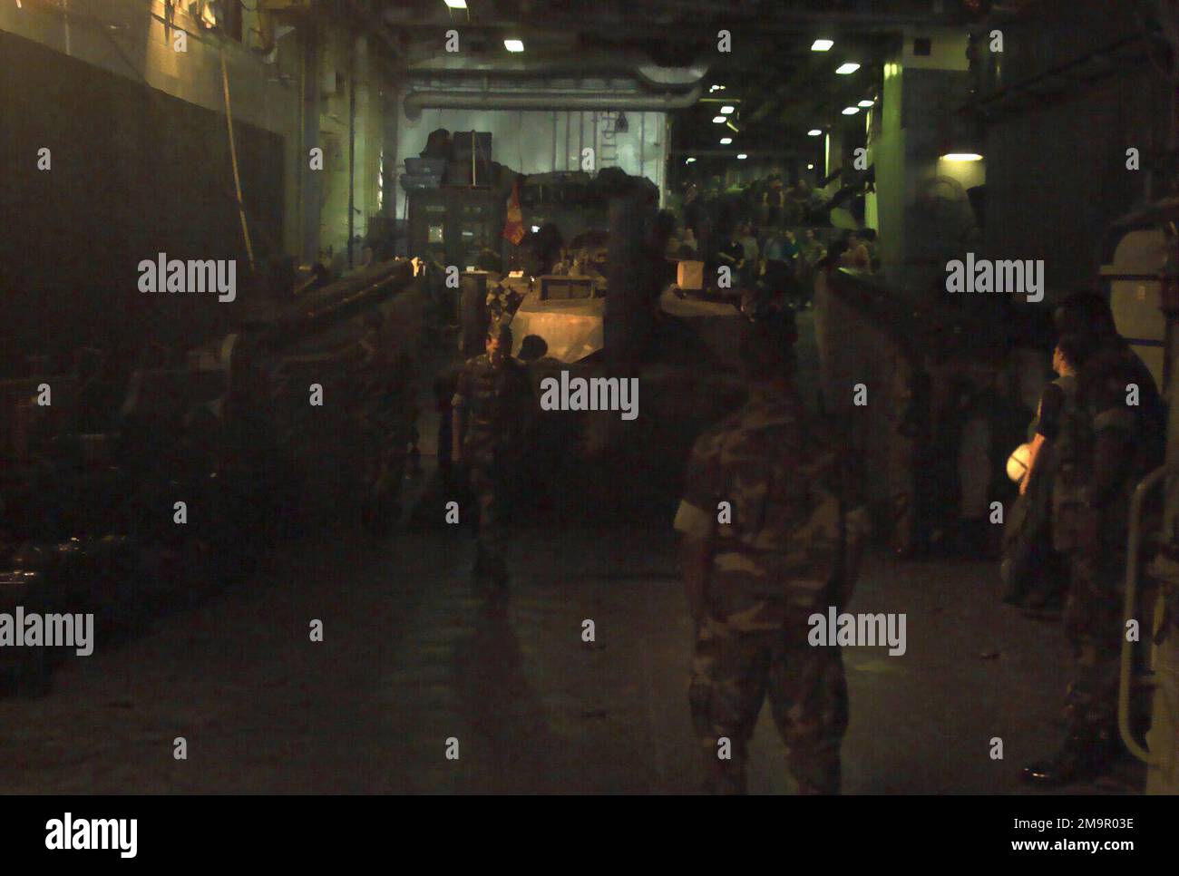 All'interno del ponte dei pozzi a bordo della nave da assalto anfibio USS NASSAU (LAH-4), USN e US Marine Corps (USMC) personale assegnato a Tank Platoon, Battaglione Landing Team (BLT), 2nd Battaglione, 2nd Marines, 24th Marine Expeditionary Unit (MEU), Special Operations Capable (SOC), Guarda come un USMC M1A1 Main Battle Tank (MBT) viene caricato su un'imbarcazione Landing Craft Utility (LCU), durante il funzionamento CHE OFFRE LA MASSIMA LIBERTÀ. (Immagine substandard). Funzionamento soggetto/Serie: BASE DI LIBERTÀ DUREVOLE: USS Nassau (LHA 4) Foto Stock