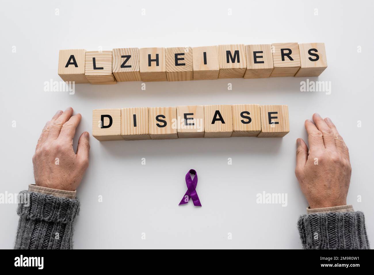 vista dall'alto di un uomo anziano corto vicino al nastro viola e cubetti di legno con la scritta della malattia di alzheimers sulla superficie bianca, immagine di scorta Foto Stock