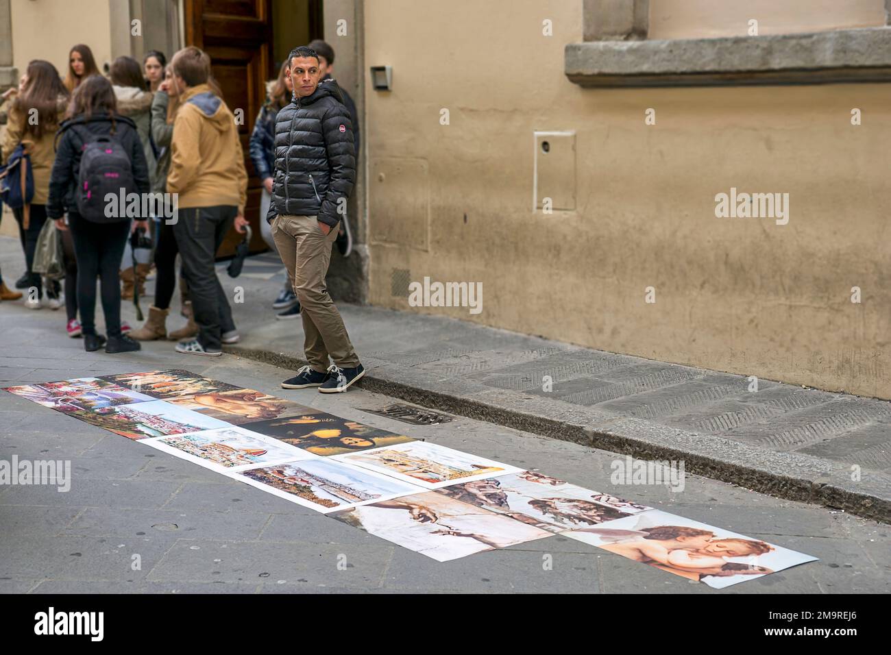 Un venditore di strada vende copie di famose opere d'arte fuori dalla Galleria dell'Accademia a Firenze. Foto Stock