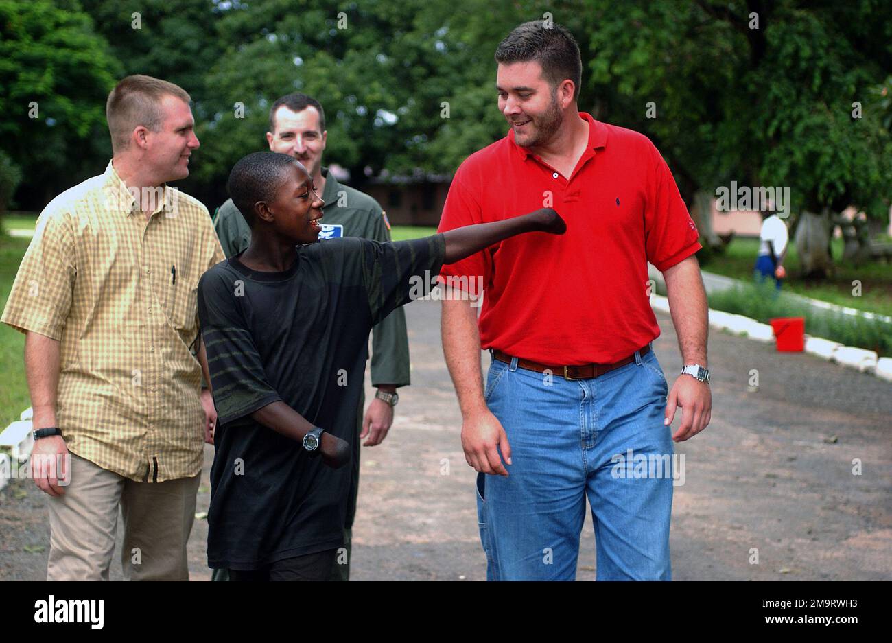 030820-F-6701P-009. [Completa] Caption scena: Abraham Bangura un sopravvissuto di 15 anni ad un attacco ribelle durante le guerre civili della Sierra Leone, parla con l'agente speciale delle forze aeree statunitensi (USAF) Vance Little (a sinistra) e SA George Breed, entrambi assegnati all'ufficio delle indagini speciali delle forze aeree (AFOSI), Schierato con il 398th Air Expeditionary Group (AGE), a Lungi Sierra Leone, durante la Joint Task Force Liberia (JTF Liberia). Abraham guardò come i ribelli uccisero suo padre nel suo piccolo villaggio di Kono, poi gli avvolse le mani in sacchetti di plastica, le mise con benzina e le mise in fuoco nella paura Foto Stock