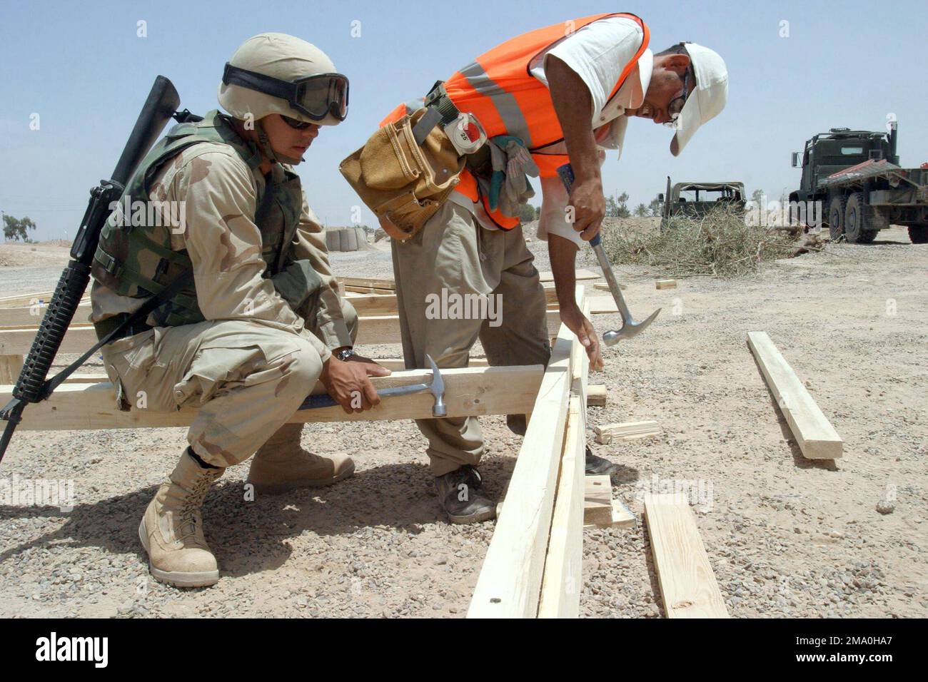 040519-M-8049T-199. Una marina statunitense (USN) Seabee assegnata al Battaglione Navale Mobile Construction Seven Four (NMCB-74), porta il suo fucile M16A2 del 5,56mm, mentre supervisiona un operaio locale iracheno durante la costruzione di un telaio per l'edificio del Fallujah Liaison Team situato al di fuori di Fallujah, in Iraq, durante l'operazione DI LIBERTÀ IRACHENA. Foto Stock