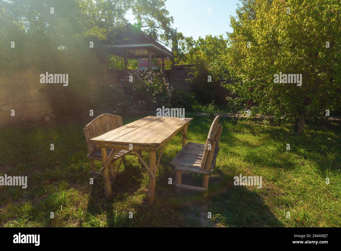 Tavolo e panchine in legno fatti a mano sull'erba nel giardino della casa di campagna Foto Stock