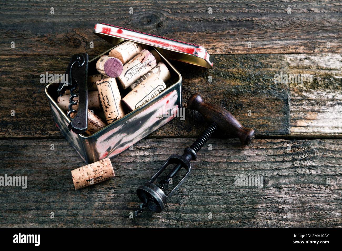 lattina di metallo vecchio con sughero e cavatappi su uno sfondo rustico di legno Foto Stock