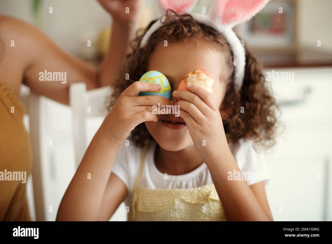 Non riesco a vederti attraverso le mie uova. Una bambina che copre l'occhio con un uovo di Pasqua dipinto. Foto Stock