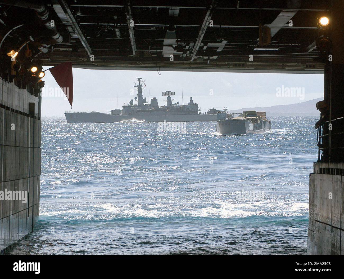 040706-N-4304S-106. [Complete] Scene Caption: A US Navy (USN) Landing Craft Utility (LCU) si avvicina al ponte del pozzo della nave da assalto anfibio USN Tarawa Class USS TARAWA (LHA-1) mentre il cileno (Armada de Chile (ACH)) Leander Class Frigate LYNCH (FFG 07) opera nelle acque appena a poppa della nave. I TARAWA e LYNCH sono due di molte navi da guerra che partecipano all'esercizio Rim of the Pacific (RIMPAC) 2004. RIMPAC è il più grande esercizio marittimo internazionale nelle acque intorno alle isole hawaiane. Questo esercizio include sette nazioni partecipanti: Australia, Canada, Cile, J Foto Stock