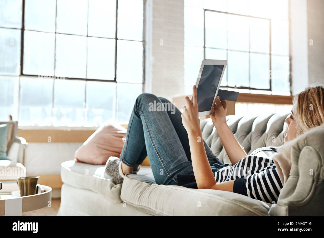 Donna, tablet e carta di credito per lo shopping online su un divano rilassante nel soggiorno per l'e-commerce a casa. Shopping femminile su touchscreen Foto Stock