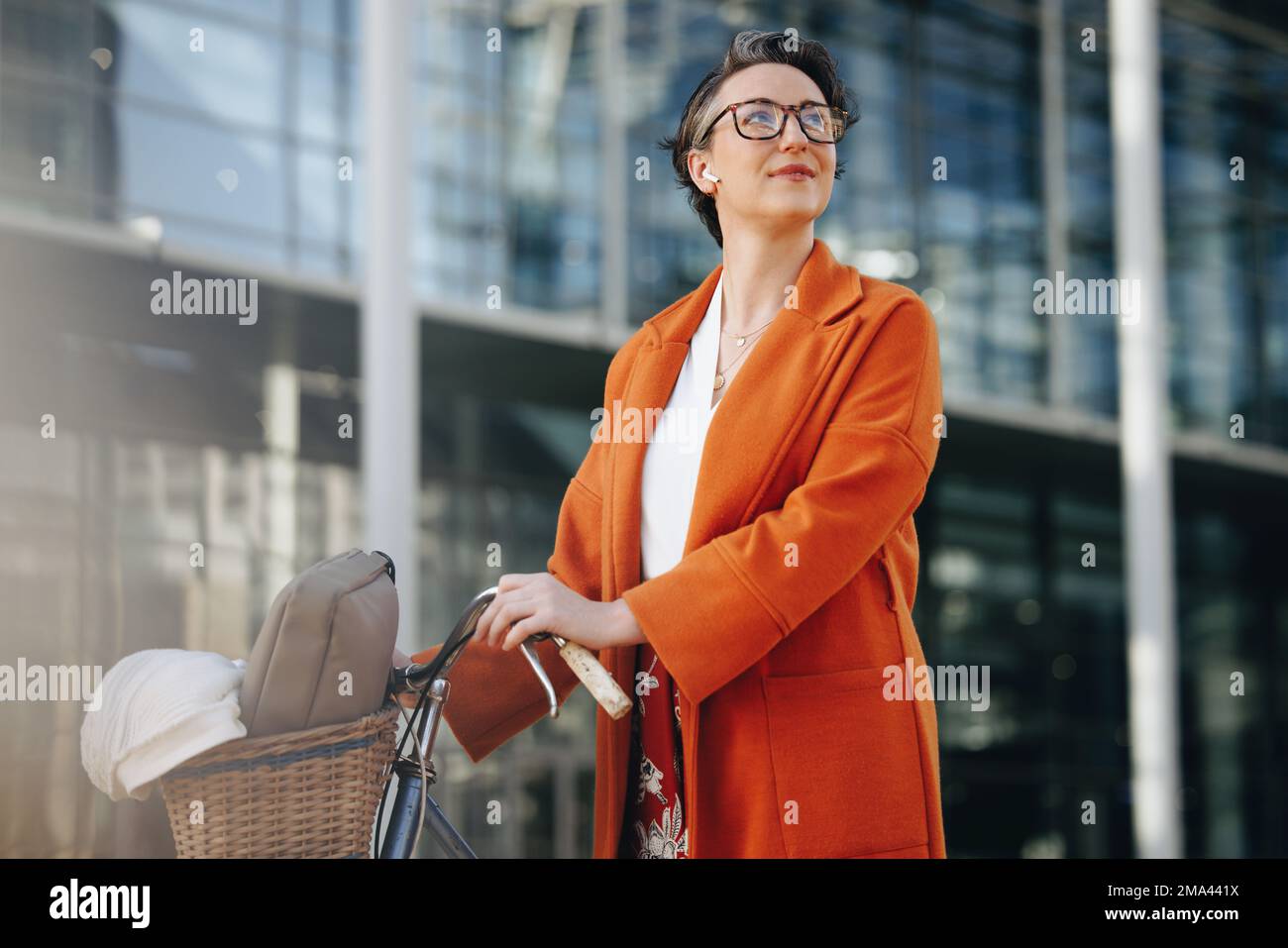 Una donna d'affari penosa che spinge la sua moto durante il suo viaggio mattutino in città. Donna d'affari matura guardando via pensieroso mentre cammina a lei di Foto Stock