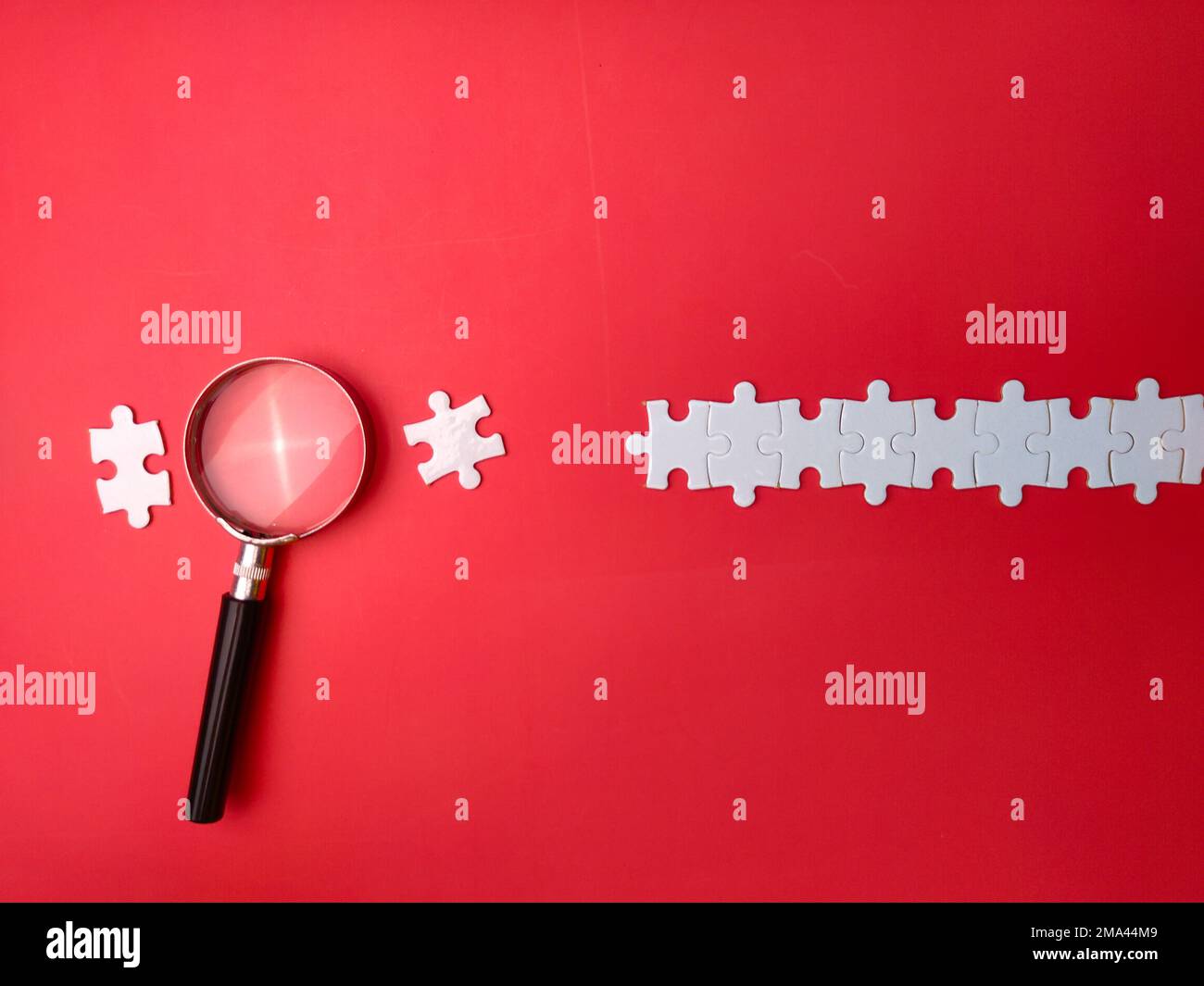 Lente di ingrandimento ricerca puzzle mancante su sfondo rosso Foto Stock