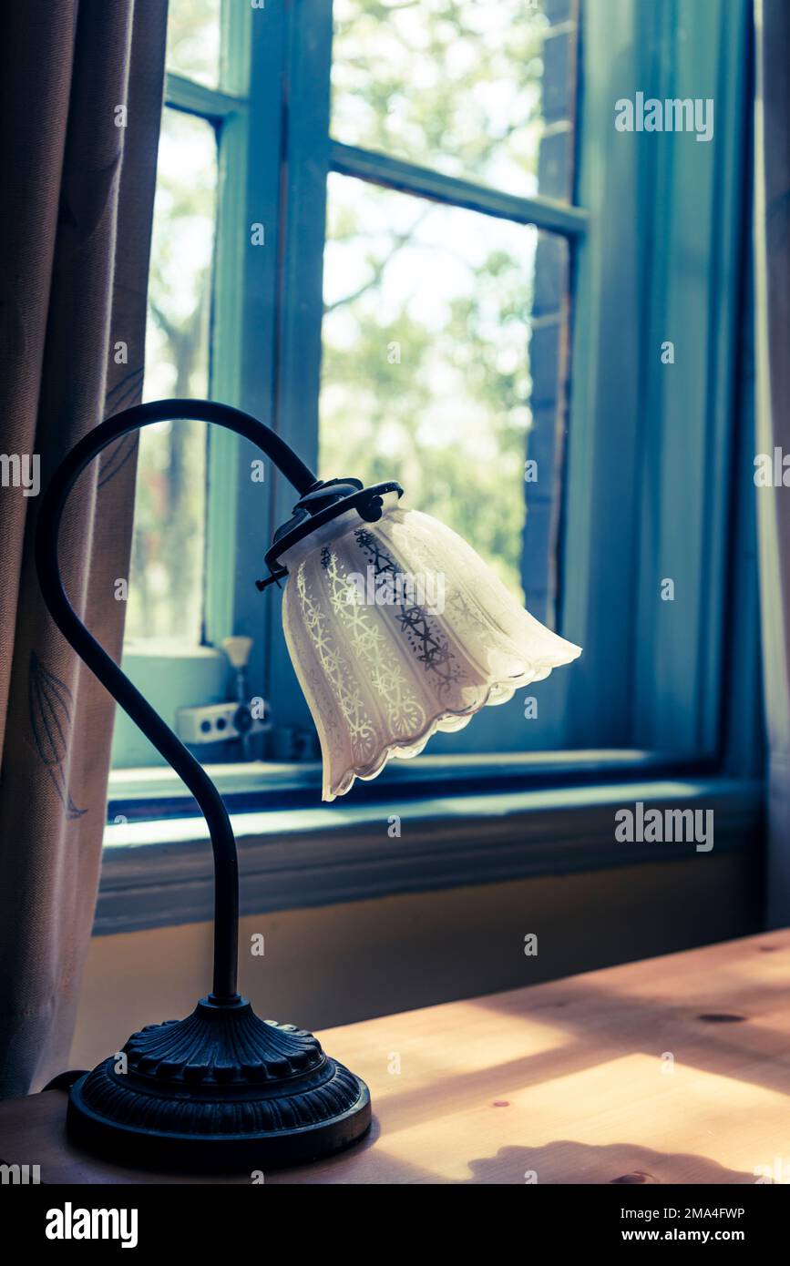 Lampada da tavolo in vecchio stile su un tavolo accanto alla finestra Foto Stock