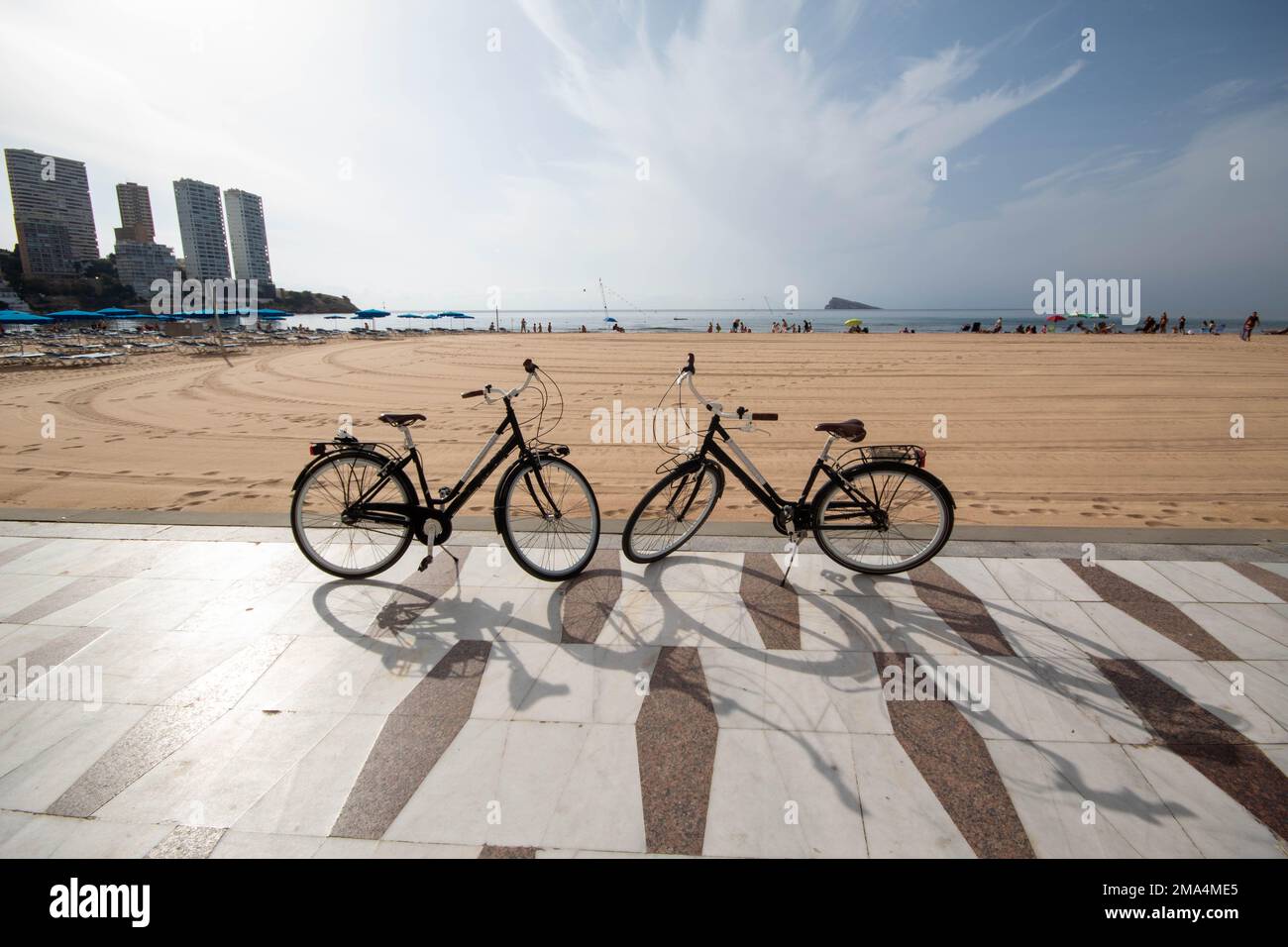 Un paio di biciclette, una di fronte all'altra, di alcuni turisti innamorati che viaggiano a Benidorm con una delle sue grandi spiagge sullo sfondo. Foto Stock