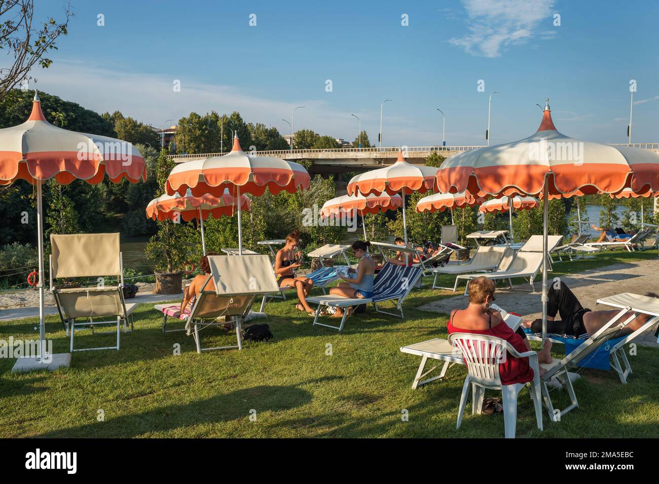 Persone sedute ai tavoli di un bar in uno stabilimento lungo le rive del fiume Tevere, vicino a Ponte Marconi, a Roma, Italia, Europa Foto Stock