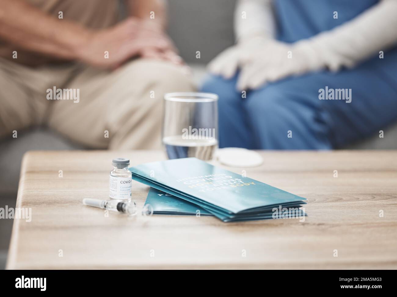 Non tutti gli angeli hanno ali, alcuni hanno scrub. un vaccino e un opuscolo su un tavolo durante un controllo a casa. Foto Stock