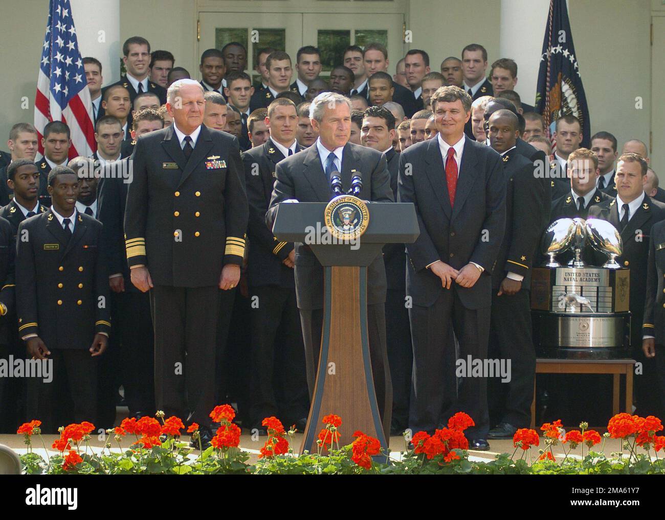 050420-N-0000A-004. [Complete] Scene Caption: Il presidente AMERICANO George W. Bush consegna le sue osservazioni durante la presentazione del Trofeo Comandante-in-CHIEF ai membri della squadra di calcio dell'Accademia Navale degli Stati Uniti (USNA) in una cerimonia al White House Rose Garden. Il presidente Bush si è congratulato con il team per aver vinto il trofeo del comandante in CAPO per il secondo anno consecutivo. Sul podio con il presidente Bush ci sono: US Navy (USN) Vice Ammiraglio (VADM) Rodney P. Rempt (a sinistra), sovrintendente della US Naval Academy, e Head Football Coach Paul Johnson (a destra). Il trofeo va ogni anno alla squadra con il miglior record i Foto Stock