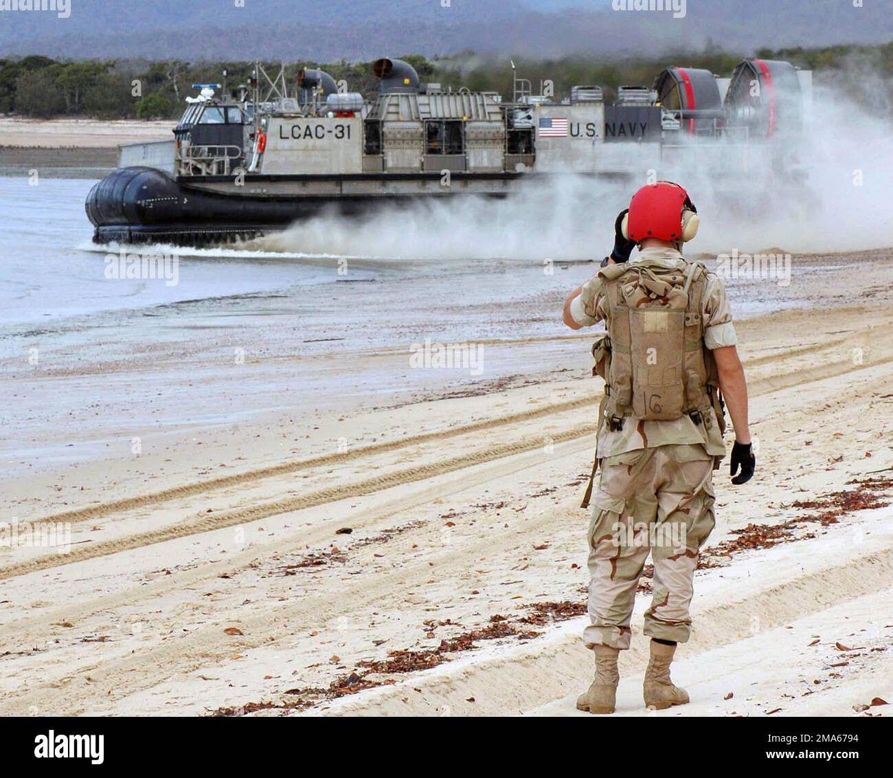 050619-N-3455P-002. [Completa] Scene Caption: Un Beachmaster US Navy (USN), Assault Craft Unit 5 (ACU-5), Marine Corps base (MCB) Camp Pendleton, California (CA), imbarcato a bordo della nave da assalto anfibio USN Wasp Class USS BOXER (LHD 4), guarda un Landing Craft USN, Il veicolo Air Cushion (LCAC) parte dopo aver lasciato i soldati dell'esercito australiano a Sabina Point durante l'esercizio DEL TALISMANO SABER 2005. TALISMAN SABER è un esercizio sponsorizzato congiuntamente dal comando del Pacifico degli Stati Uniti (USPACOM) e dal comando delle operazioni congiunte della forza di difesa australiana, e progettato per formare lo staff del comandante della flotta degli Stati Uniti 7th e. Foto Stock
