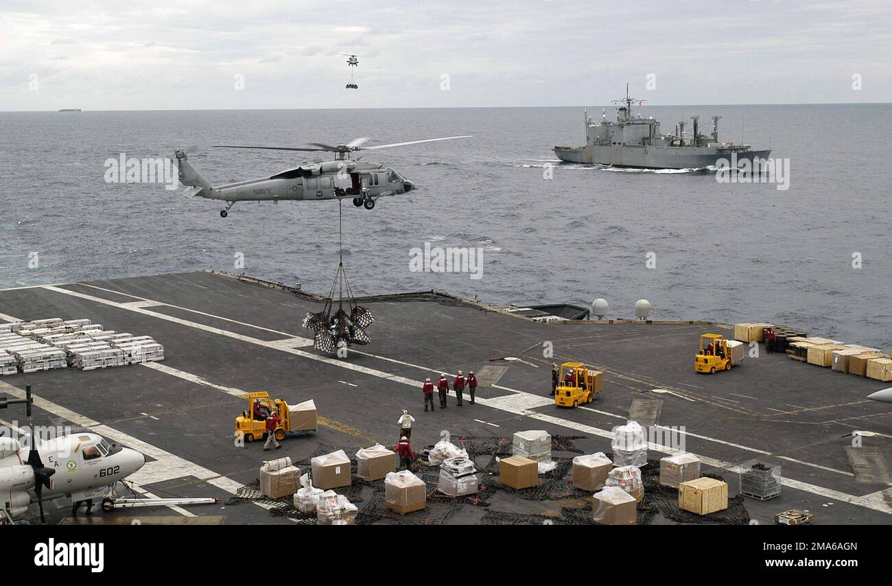 050627-N-0167B-021. [Complete] Scene Caption: A US Navy MH-60s Seahawk elicottero, da elicottero Sea Combat Squadron 25, trasporta carichi a bordo del portaerei USS KITTY HAWK (CV 63) dalla nave militare Sealift Command Kilauea classe munizioni USNS FLINT (T-AE 32), sullo sfondo, Durante un'operazione di rifornimento verticale tra le due navi durante l'esercizio Talisman Sabre 2005 al largo della costa della regione del Queensland in Australia il 27 giugno 2005. Talisman Sabre è un statunitense Pacific Command Esercitazione progettata per formare gli Stati Uniti Settimo comandante della flotta e comuno australiano Foto Stock