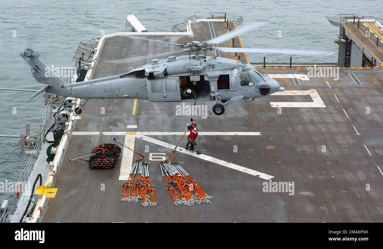 A bordo della US Navy (USN) Tarawa Class: Nave da assalto anfibio, USS PELELIU (LHA 5), due membri dell'equipaggio della Red Shirt Ordnance attaccano un pendente di carico a un elicottero MH-60s KnightHawk, assegnato ai 'Blackjack' dell'elicottero Sea Combat Squadron due (HSC-21), Mentre la nave opera nell'Oceano Pacifico, si prepara per un imminente spiegamento nell'Oceano Pacifico occidentale. Base: USS Peleliu (LHA 5) Nazione: Oceano Pacifico (POC) Foto Stock