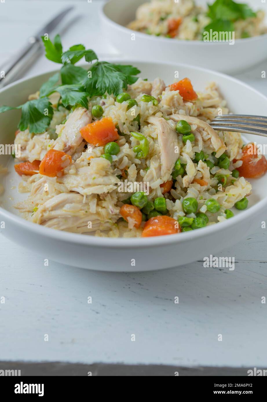Far rosolare il riso con pollo e verdure. su un piatto con coltello e forchetta su fondo bianco. pasto sano per fitness, dieta o alimentazione sana Foto Stock