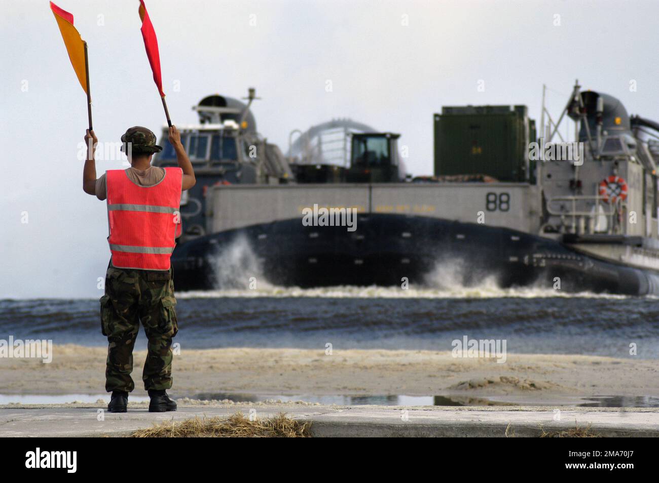 Un COMANDANTE della marina statunitense (USN) Beach, Beach Masters Unit Two (BMU-2), dirige un cuscino d'aria dell'imbarcazione da atterraggio (LCAC), Assault Craft Unit Four (ACU-4), caricato con attrezzature pesanti del corpo marino statunitense (USMC) su una spiaggia vicino a Biloxi, Mississippi (MS), per la pulizia in seguito dell'uragano Katrina. Base: Biloxi Stato: Mississippi (MS) Paese: Stati Uniti d'America (USA) Foto Stock