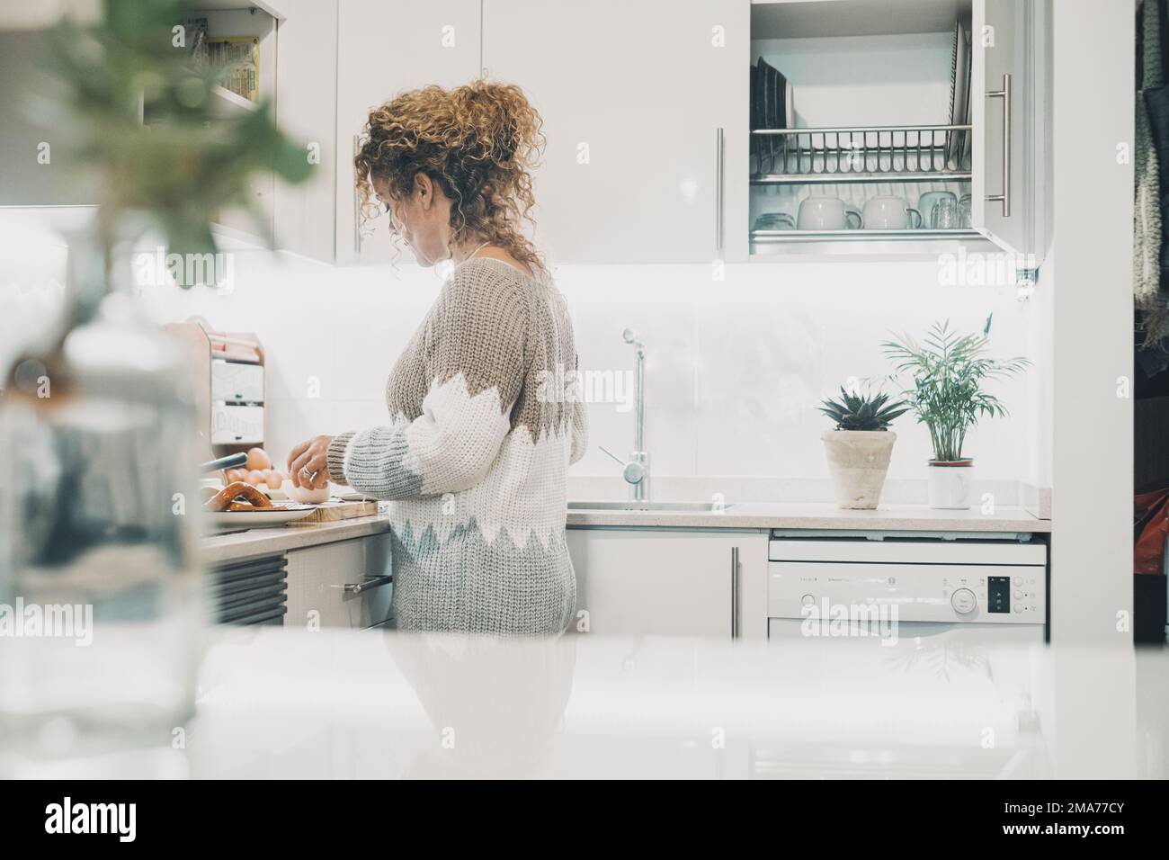 Una donna sola in cucina nella vita reale che prepara il cibo per il pranzo. Concetto di stile di vita per una sola donna. Interni bianchi stile minimalista. Tempo libero al coperto Foto Stock