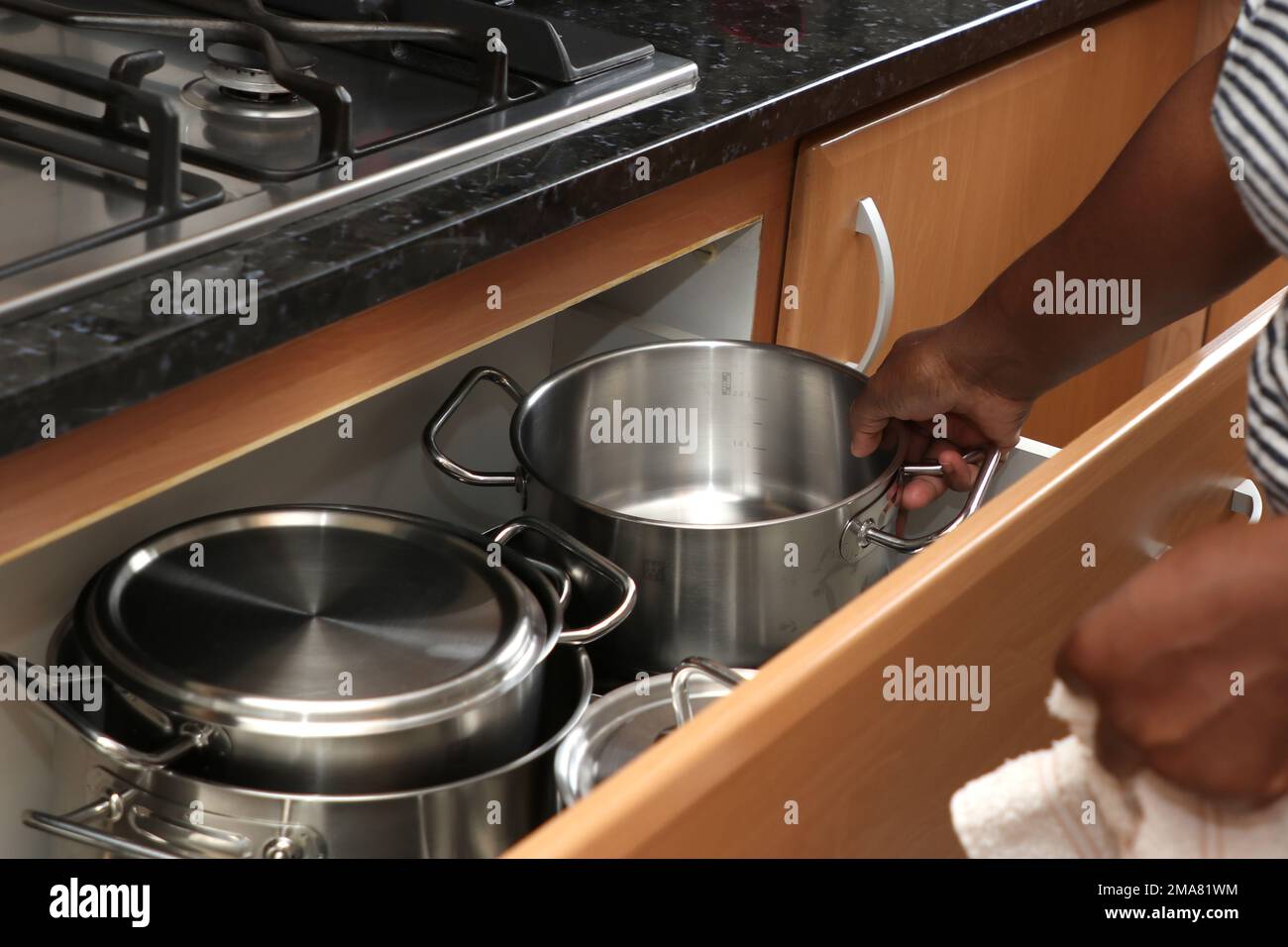 Una donna africana che asciuga una pentola da cucina con un asciugamano in cucina Foto Stock